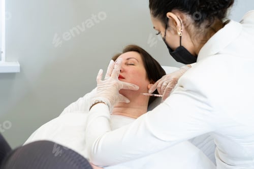 Preview: Clinician treats double chin with lipolytics, patient relaxed. Reflects advancements in non-surgical