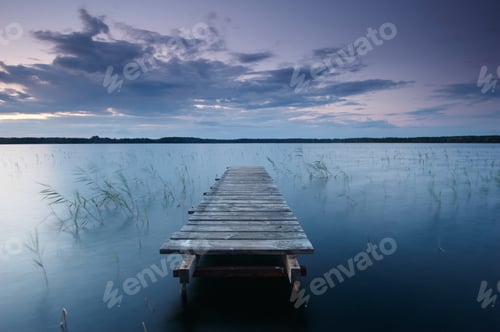 Preview: Colorful landscape with sky and wooden jetty pier reflected in the lake at evening