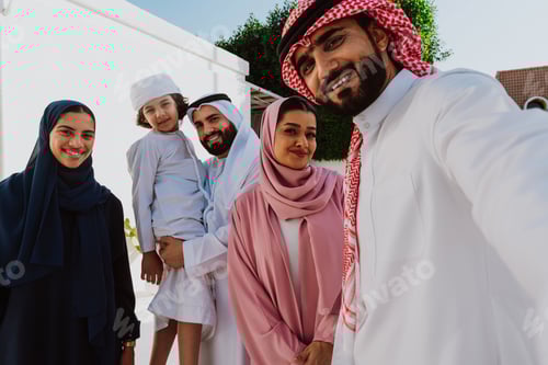 Preview: Emirati family standing together smiling in traditional attire