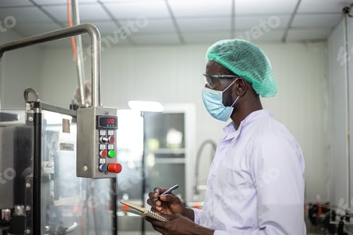 Preview: African American male worker inspecting drink product on machine