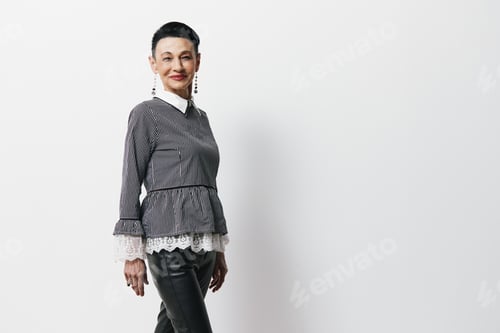 Preview: A woman in a grey sweater and black pants smiles in front of a white wall