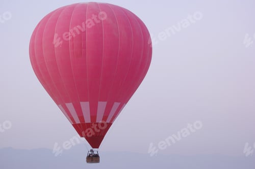 Preview: Red hot air balloon with a tourists flying in the morning sky.