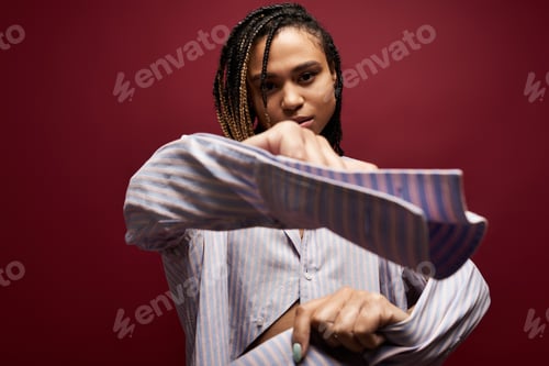 Preview: Stylish African American woman with braids showcases her fashion in a vibrant studio