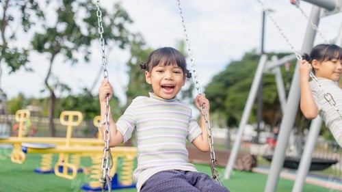 Preview: A little girl is having fun riding a swing.