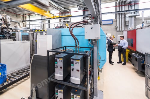 Preview: Two men talking among machines in factory shop floor