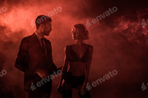 Preview: Beautiful couple amorously looking at each other on red smoke background