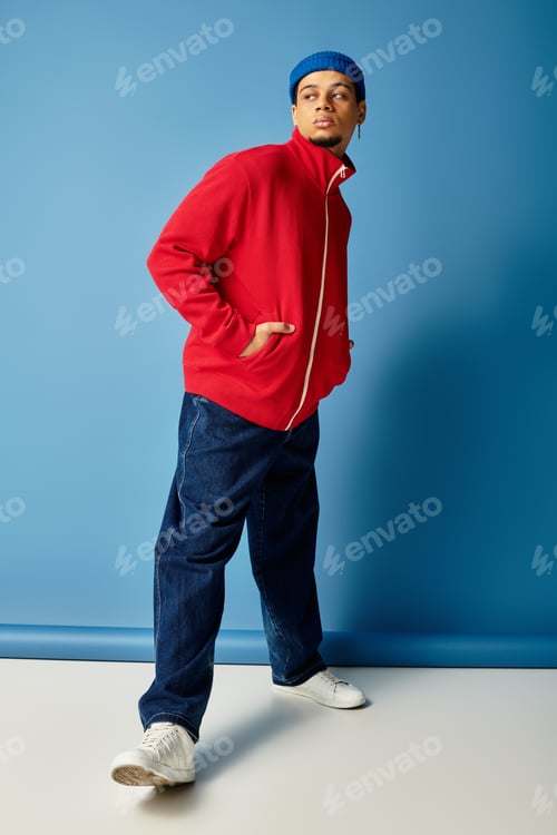 Preview: Stylish young Black man flaunts trendy fashion against a vibrant blue backdrop