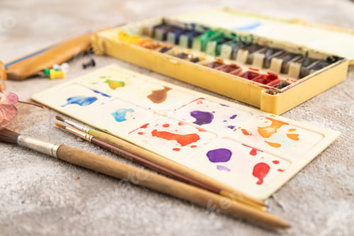 Preview: Drawing accessories set: brushes, pencils, watercolor on brown concrete. Side view, selective focus