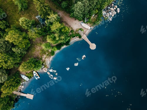 Preview: Aerial view of wooden cottage in green forest by the blue lake in rural summer Finland