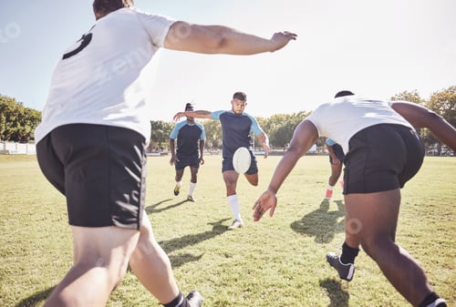 Preview: Mixed race rugby player attempting a dropkick during a rugby match outside on the field. Hispanic m