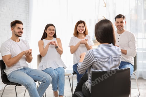 Preview: Group of young people learning sign language with teacher indoors