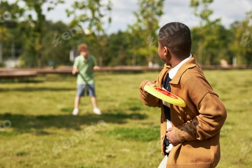 Preview: Black Boy Throwing Disc Toward Caucasian Boy during Outdoor Playtime