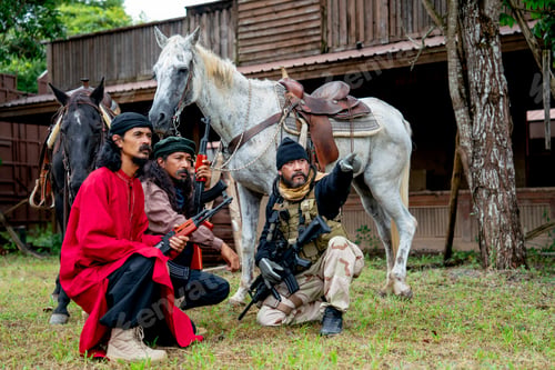 Preview: Group of men with soldier and arab clothes sit down in front of horse and old building