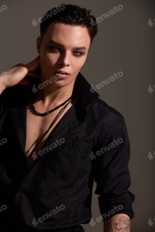 Preview: Studio portrait of a young teenager brunette boy in a black shirt with beads around his neck. Short