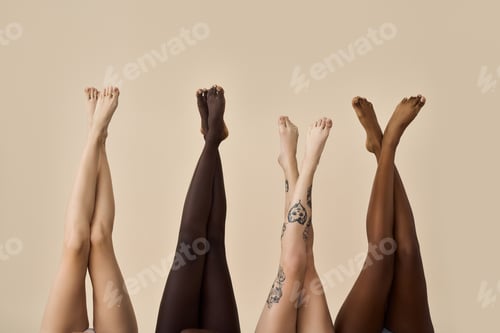 Preview: Diverse female legs raised up on beige background. Hair removal concept.