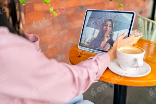 Preview: Freelancer working remotely from coffee shop, video calling on tablet