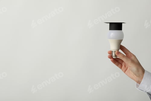 Preview: A university graduate hat on a light bulb, on a gray background.