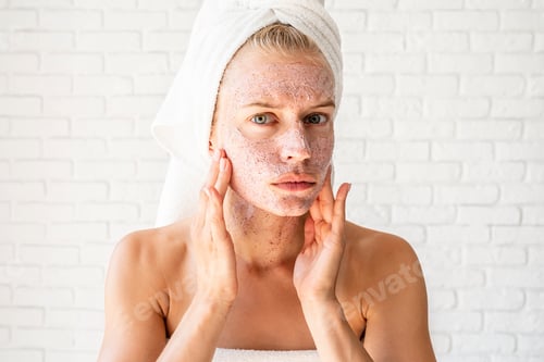 Preview: Preoccupied young woman in white bath towels applying scrub on her face