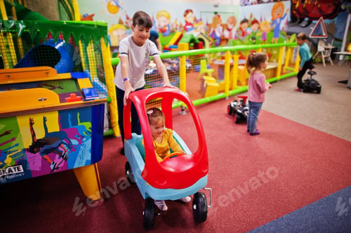Preview: Four kids playing in indoor play center. Kindergarten or preschool play room. Riding toy car.