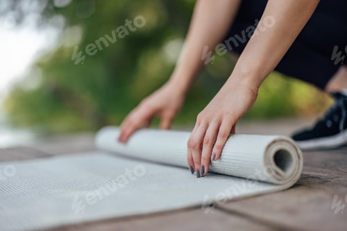 Preview: Woman Rolling Up Yoga Mat Outside for Exercise