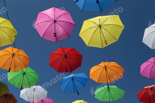Preview: Array of vibrant umbrellas of various hues float in the sky against a cloudless blue backdrop