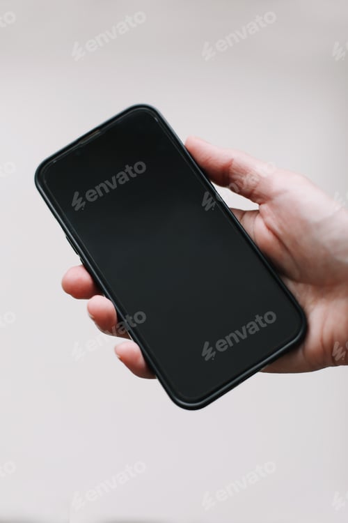 Preview: Close up of woman hand using smartphone isolated on white wall. Female hand showing empty screen of
