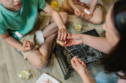 Preview: Top view of unrecognizable family making smores at home