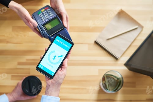 Preview: Top view of hands of clerk with payment terminal and client with smartphone
