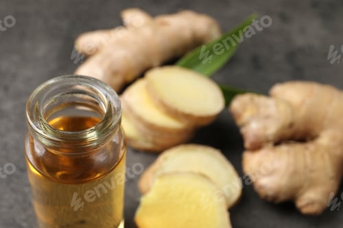 Preview: Glass bottle of ginger essential oil on grey table, closeup. Space for text