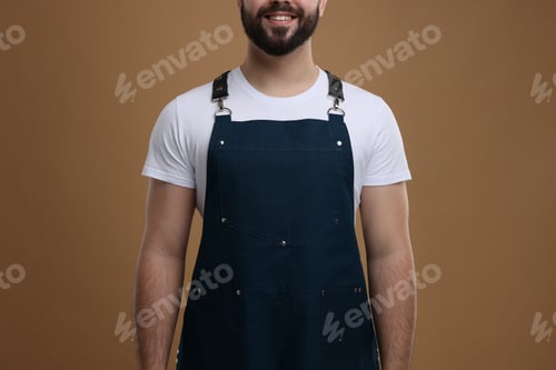 Preview: Smiling man in kitchen apron on brown background, closeup. Mockup for design
