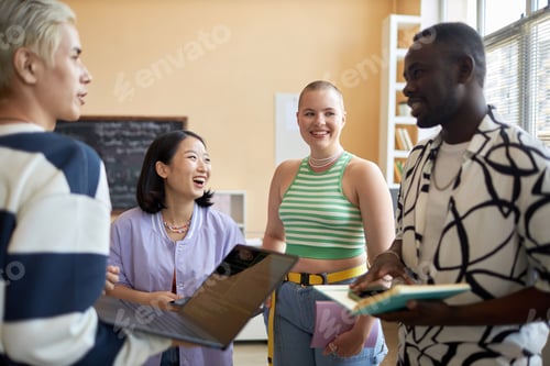 Preview: Young laughing Asian woman and her classmate looking at African American guy