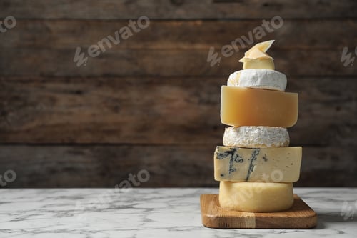 Preview: Different types of delicious cheese on marble table against wooden background, space for text
