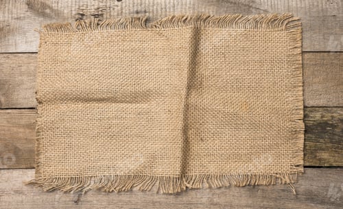Preview: Brown burlap fragment on gray wooden background,