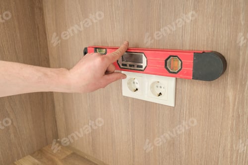 Preview: Hands of electrician worker installing electrical outlet in furniture