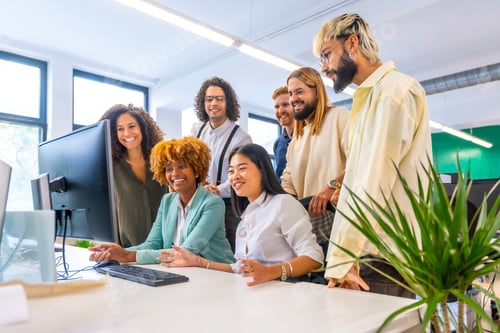 Preview: Coworkers using computer together and smiling looking the screen