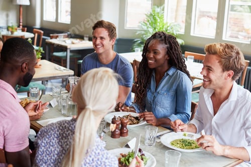 Preview: Group Of Friends Sitting At Table In Restaurant Enjoying Meal Together