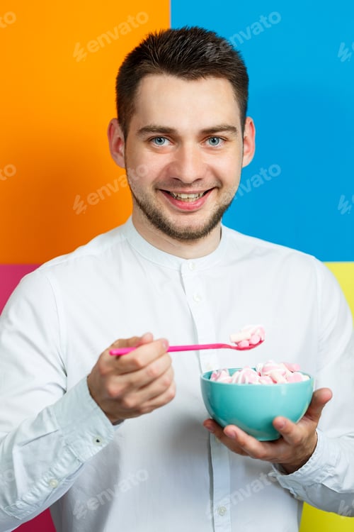 Preview: Young Man Enjoys Marshmallows on a Colorful Background