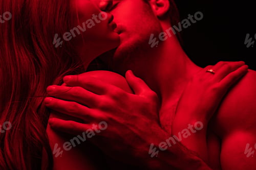 Preview: cropped view of passionate sexy young couple kissing in red light isolated on black