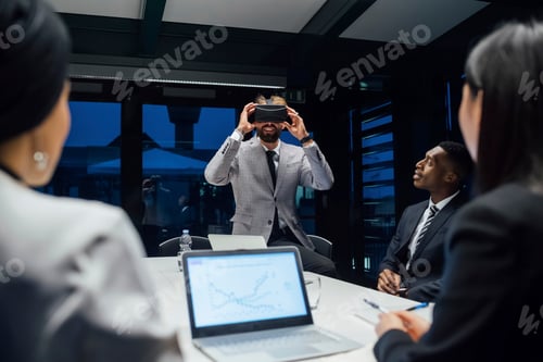 Preview: Businessman looking through virtual reality headset during conference table meeting