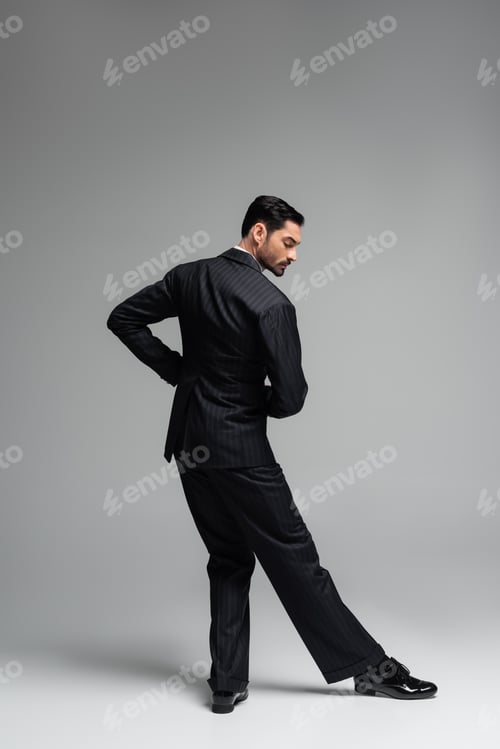 Preview: Side view of elegant dancer in suit moving on grey background