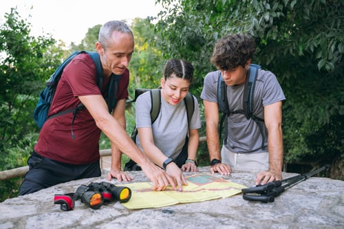 Preview: Family hiking team finding way using map on trail