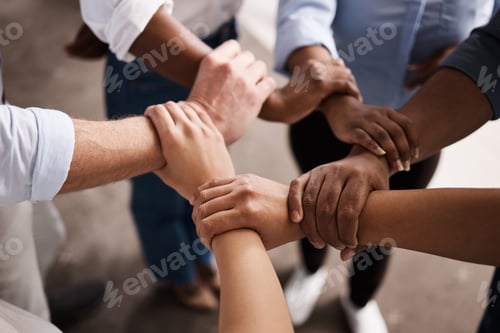 Preview: Cropped shot of a group of businesspeople linking their arms in solidarity at work
