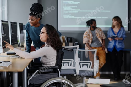 Preview: Black Girl and IT Specialist in Wheelchair Writing Code Together in Office
