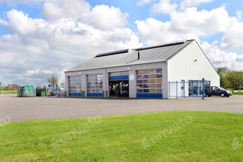 Preview: A car workshop or garage with doors open and cars on the forecourt.