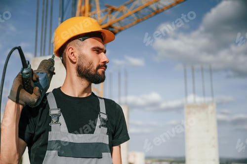 Preview: Portrait of man that is in uniform with the drill on the construction site