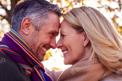 Preview: Loving Mature Retired Couple Hugging Against Autumn Countryside With Flaring Sun