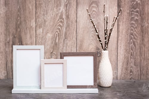 Preview: Three empty photo frames on the stand and a vase with artificial willow branches are on the table.