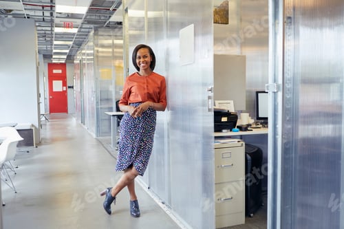 Preview: Portrait of businesswoman standing in office corridor, leaning against office surround, smiling