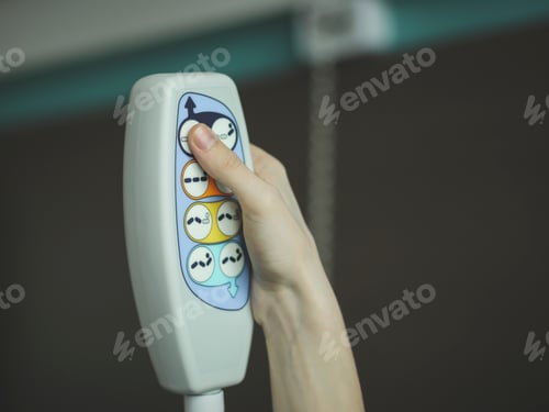 Preview: The hand of a young caucasian male holds a medical bedside remote control and presses a button