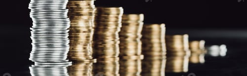 Preview: selective focus of stacked silver and golden coins on surface with reflection isolated on black,